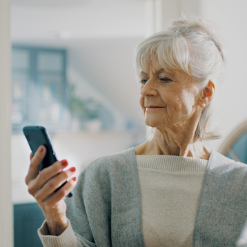 Kvinna använder Doro-telefon sittande vid flod.